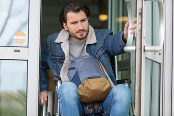 man in a wheelchair getting out of building