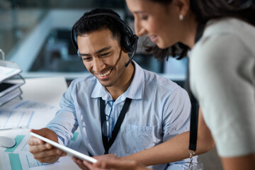 The customer care department is getting bigger by the day. Shot of a young man and woman using a digital tablet while working in a call centre.