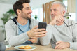 © auremar - excited elderly dad and grown-up son browsing internet on smartphone