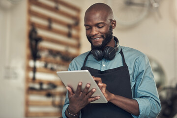 Aufkleber - Clients are emailing already. Shot of a handsome young man standing alone in his bicycle shop and using a digital tablet.