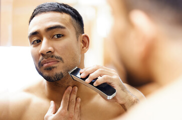 My date wont even recognise me tonight. Shot of a young man using an electric shaver.