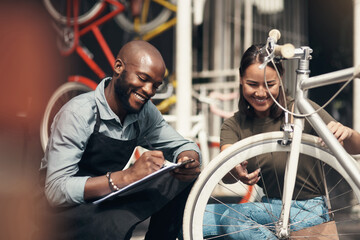 Wall Mural - Can I have your details please. Shot of a handsome young man crouching outside his bicycle shop and assisting a customer.