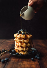 Maple Syrup Being Poured Over Stack Of Belgian Waffles With Berries.
