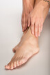 © LIGHTFIELD STUDIOS - partial view of barefoot woman touching legs with perfect skin on white background
