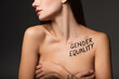 © LIGHTFIELD STUDIOS - partial view of young woman with gender equality inscription on body covering breast with hands isolated on dark grey