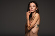 © LIGHTFIELD STUDIOS - nude and tattooed woman with freedom of speech phrase written on arm isolated on dark grey