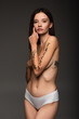 © LIGHTFIELD STUDIOS - slim woman with tattoo and freedom of speech lettering on body isolated on dark grey