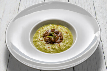 Poster - Vegetable risotto with duck stew, in a white plate on white wooden tables