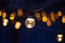 Electric Lamp Garlands With Different Size Bulbs Hanging In A Cafe, Attached To The Ceiling. Evening Party Or Wedding Decorations. Outdoor Patio String Light-Connectable Globe Lights