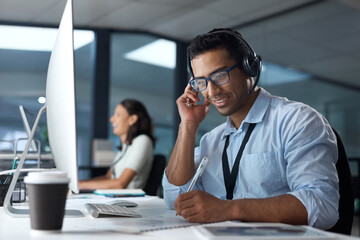 Canvas Print - Finding solutions from the very first call. Shot of a young man using a headset and computer in a modern office.