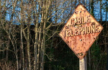 A Rusty Retro Cable Telephone Sign Basks In Sunlight. Rich Warm Colors And Copy Space Perfect.