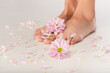 © LIGHTFIELD STUDIOS - partial view of female legs near chrysanthemum flowers and petals on white background