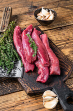 Raw Lamb Tenderloin Fillet Meat On Butcher Board With Meat Cleaver. Wooden Background. Top View