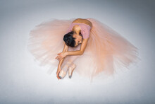 Tired Ballerina Sitting On A Light Background Background