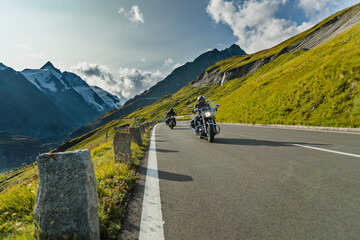 Wall Mural - Motorbiker riding in Austrian Alps in beautiful sunset dramatic sky. Travel and freedom, outdoor activities