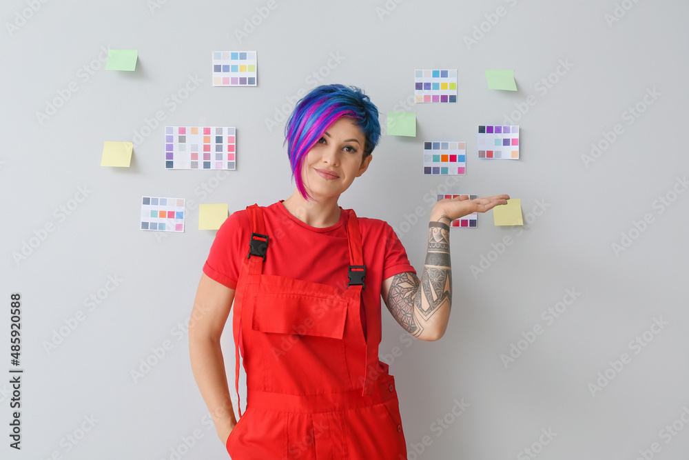 Female painter with sticky notes and palettes on light background