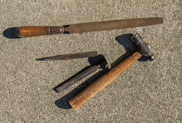 Several old rusty shop tools including a ball peen hammer and a bastard mill file