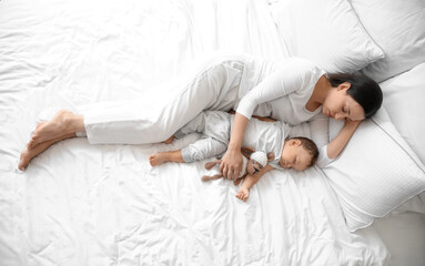 Sticker - Young mother and her adorable baby with toy sleeping on bed