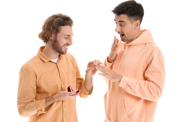 Wall Mural - Young gay putting engagement ring on his boyfriend's finger against white background