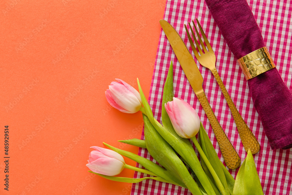 Stylish cutlery with tulip flowers on coral background