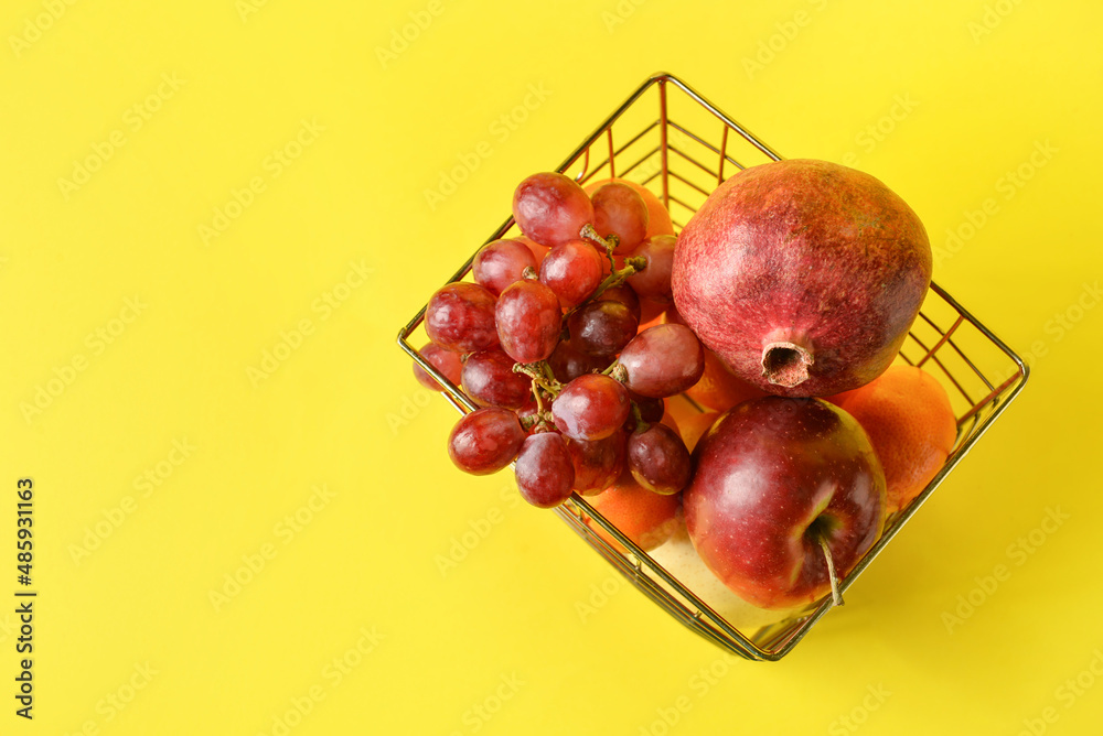 Basket with fresh juicy fruits on color background