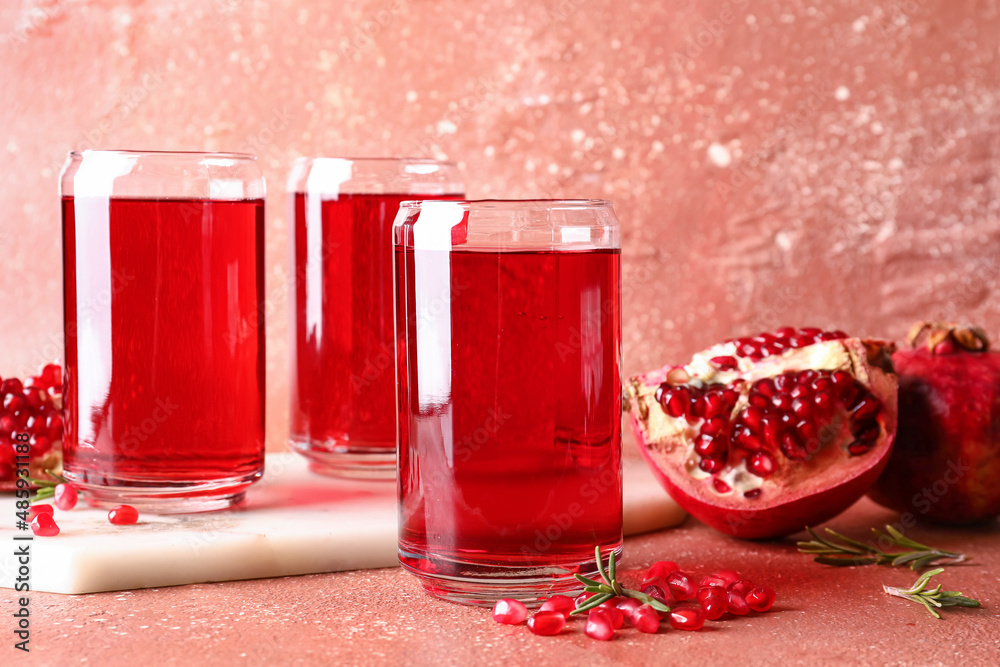 Glasses of delicious pomegranate juice on red background