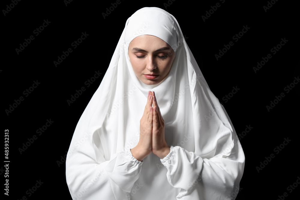 Muslim woman praying on dark background