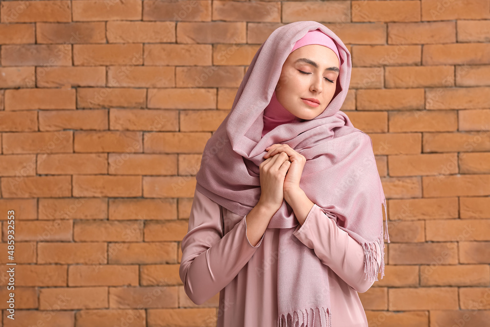 Beautiful Muslim woman on brick background