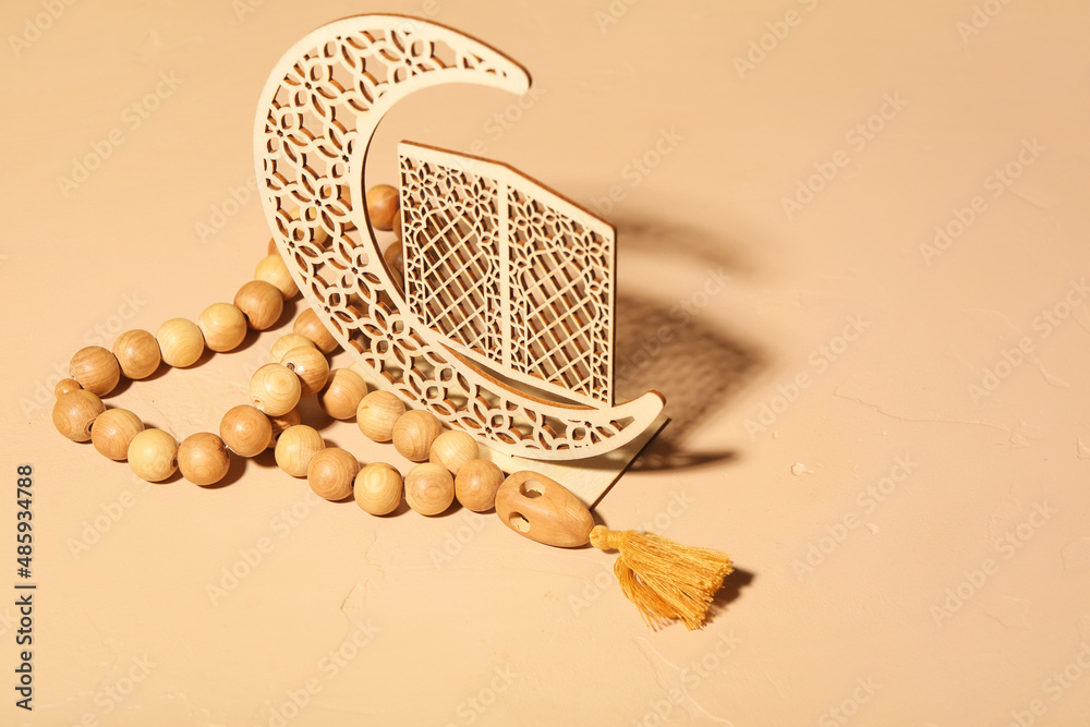 Decorative crescent and Muslim prayer beads on color background