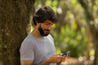 © Buonaventura - View of young man using a smartphone at day time with a green park in the background. High quality photo