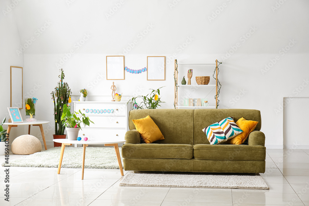 Interior of light living room with green sofa and Easter eggs