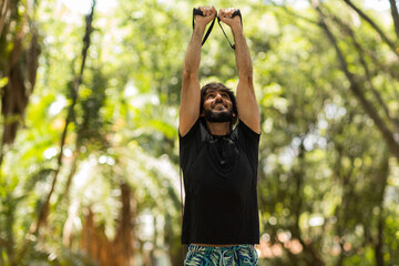 Strong man guy working out with elastic rubber bands at a park outdoors. Athlete male person during workout with additional sport equipment. High quality photo