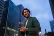 © Buonaventura - View of young man using a smartphone at night time with city view landscape in the background. High quality photo