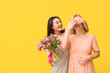 Beautiful woman with bouquet of flowers greeting her friend on color background. International Women's Day celebration