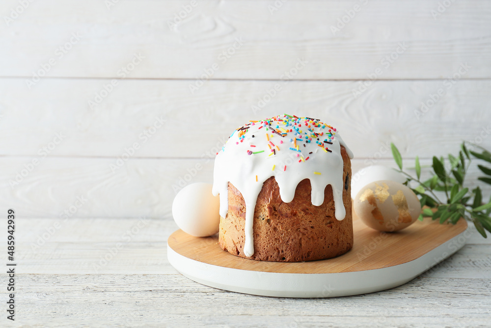 Board with delicious Easter cake and eggs on white wooden background