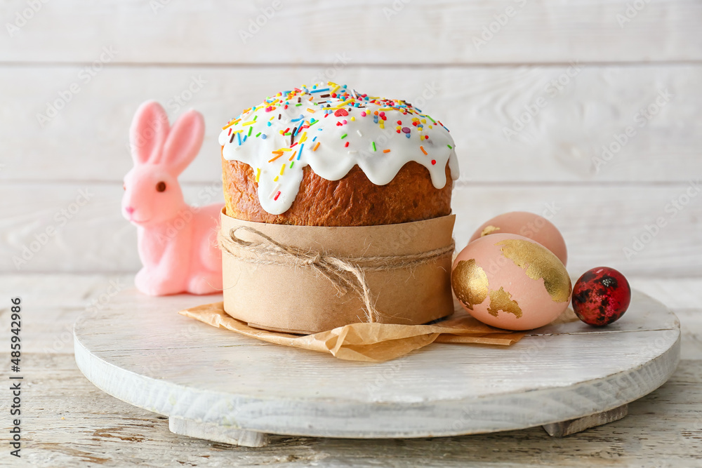Board with delicious Easter cake and eggs on white wooden background