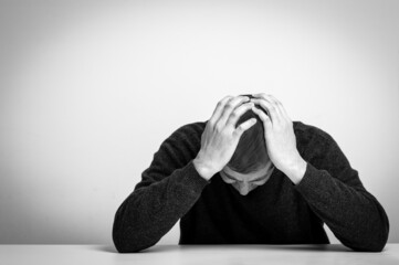 Homeless man drug and alcohol addict sitting alone and depressed home feeling anxious and lonely, black and white