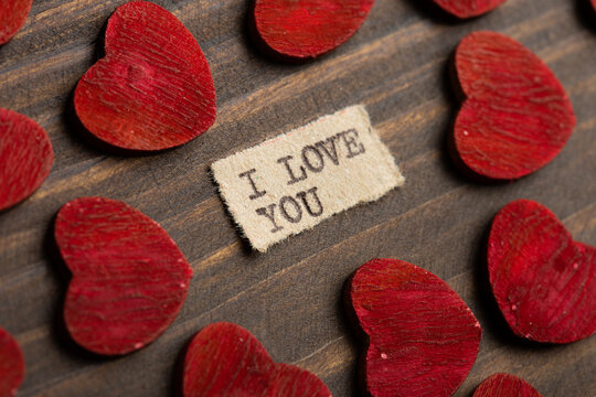 I love you - typed text. Valentines Day greetings concept. Little red wooden hearts close up. Valentines greeting card.
