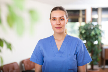 Wall Mural - Portrait of friendly female doctor wearing uniform standing in modern clinic