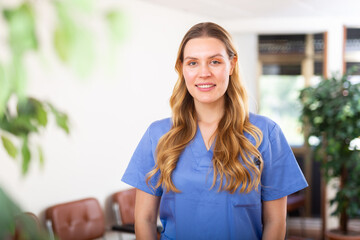 Wall Mural - Portrait of friendly female doctor wearing uniform standing in modern clinic