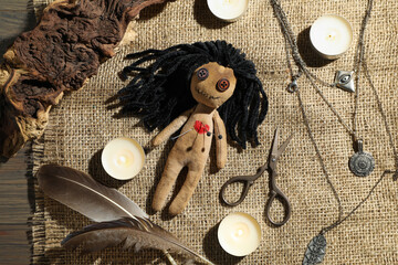 Wall Mural - Voodoo doll with pins surrounded by ceremonial items on wooden table, flat lay