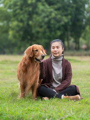 Wall Mural - Golden Retriever accompanies owner on grass in park