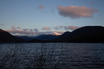 Wall Mural - A landscape of a lake and mountains with dark clouds in the background
