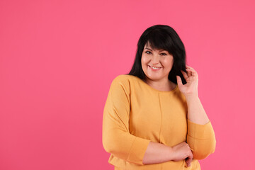 Wall Mural - Beautiful overweight mature woman with charming smile on pink background. Space for text