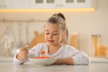 Canvas Print - Cute little girl eating tasty pasta at table in kitchen