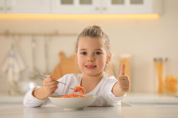 Canvas Print - Cute little girl eating tasty pasta at table in kitchen