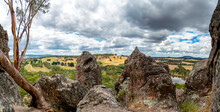 A Panoramic View From Hanging Rock In Victoria, Australia, With Volcanic Boulders In The Foreground And Rolling Hills In The Distance