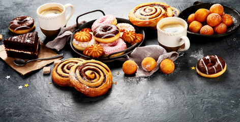 Table with various cookies, donuts, cakes and coffe cups