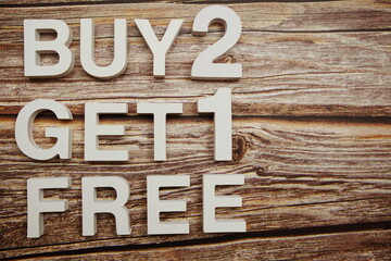 buy 2 get 1 free alphabet letters on wooden background