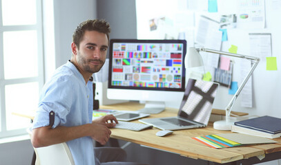 Poster - Portrait of young designer sitting at graphic studio in front of laptop and computer while working online.
